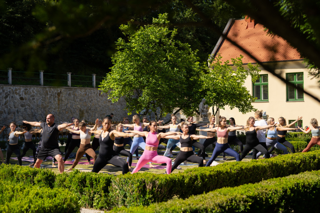 Skupina žiev cvičí jógu v záhrade kaštieľa